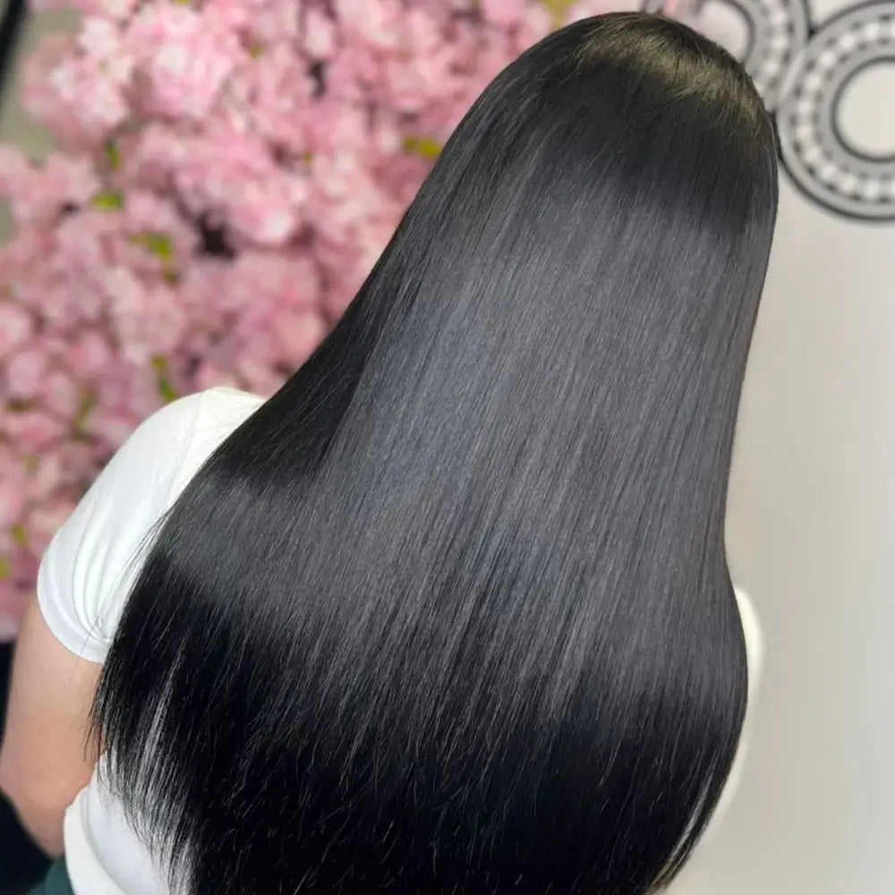 Stunning ultra-long, mirror-straight jet black hair extensions by gdollshair creating breathtaking length and shine against dreamy pink cherry blossoms.